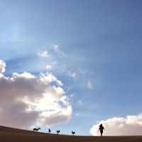 a person walking on a sand dune under a blue sky
