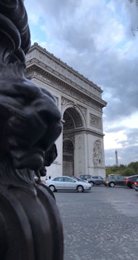 a statue of a lion in front of the arc de triomphe