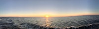 a panoramic view of the sun rising over the ocean