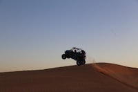 a person riding an atv on top of a sand dune