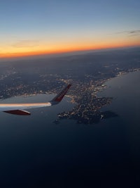a plane wing flying over a city at dusk